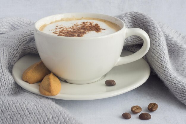 A white cup of cappuccino with ginger biscuit