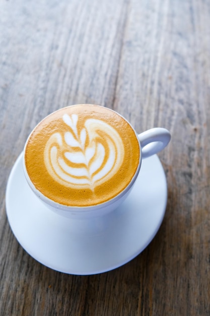 White cup of cappuccino on wooden background with beautiful latte art