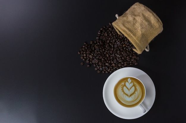 White cup of coffee and bean on black background 