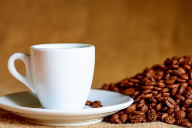 White cup and coffee beans on blurred.