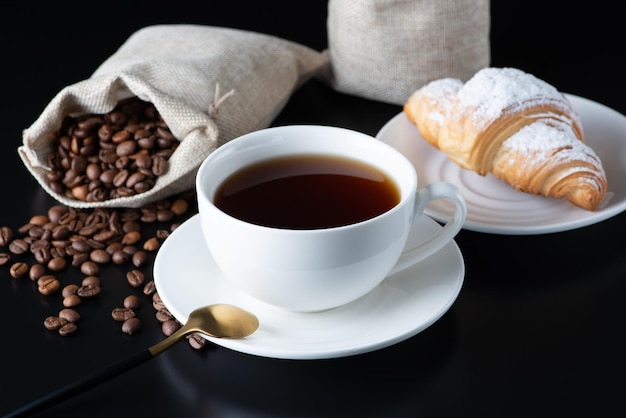 A white cup of coffee and croissant