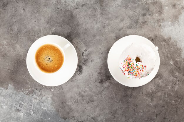 White cup of coffee and donut on grey background