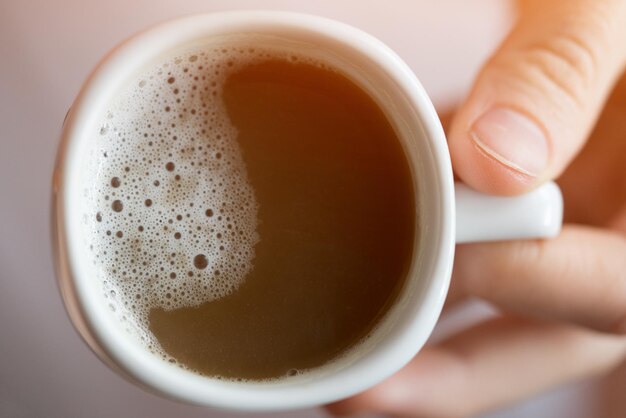 White cup of coffee in hand Toned