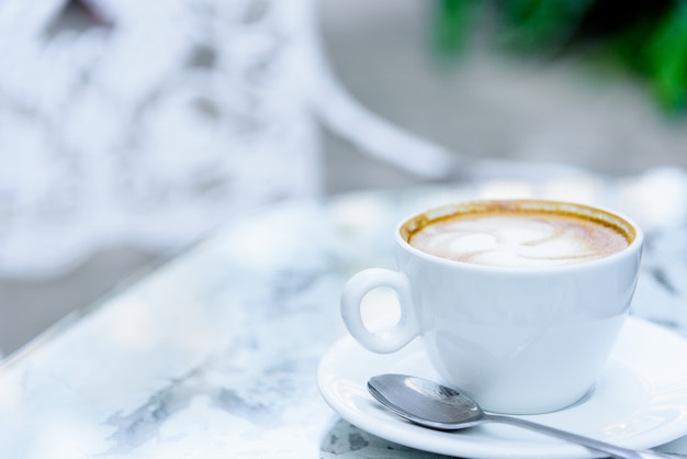 Una tazza di caffè e un computer portatile bianchi pronti a lavorare di mattina