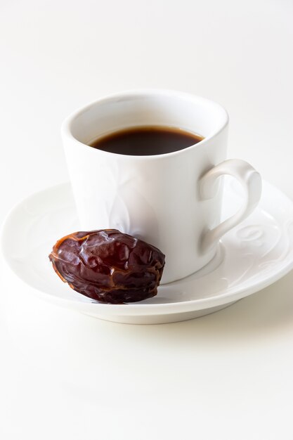 White cup of coffee and one dates white background isolated.