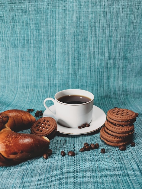 파란색 배경에 흰색 커피 한 잔과 둥근 갈색 쿠키