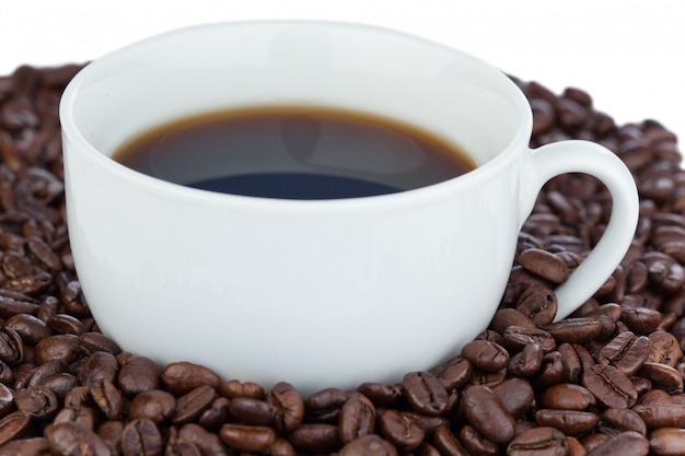 White cup of coffee surrounded with coffee beans