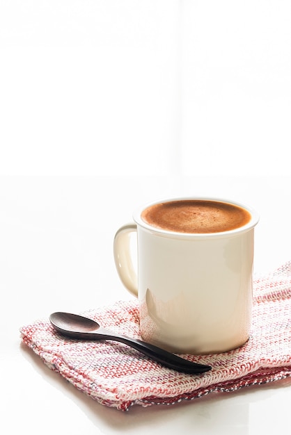 White cup of coffee on white table with bright 