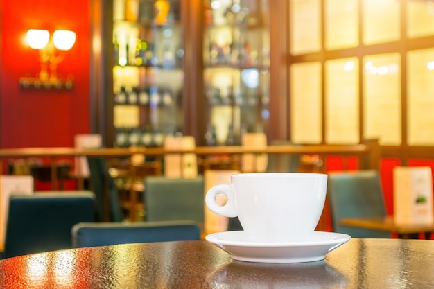 White cup of coffee on a wooden table in a cafe.