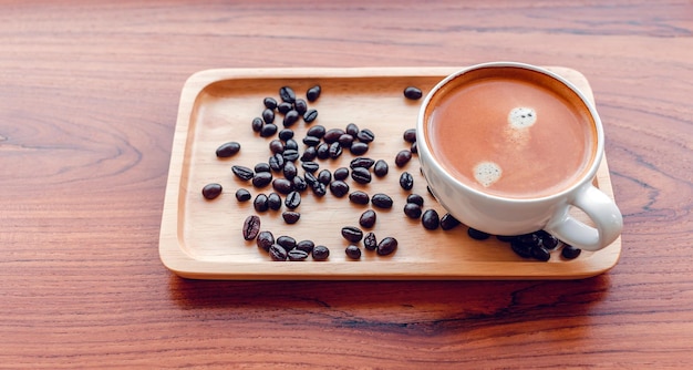 White cup of espresso coffee and Roasted coffee beans on a wooden tray