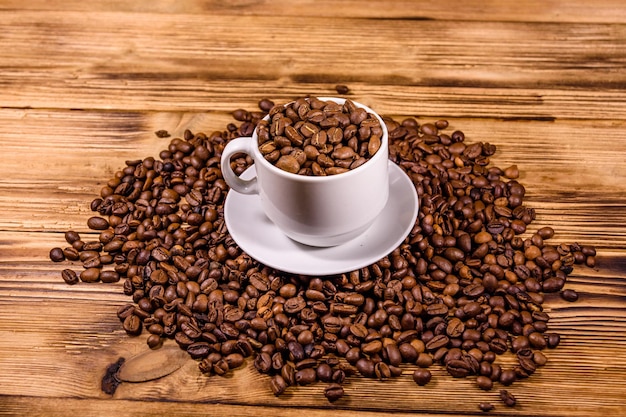 White cup filled with coffee beans on rustic wooden table