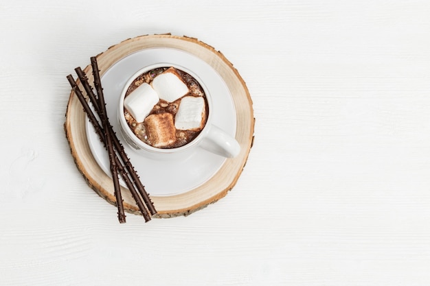 Tazza bianca di cioccolata calda con marshmallow e bastoncini di cioccolato