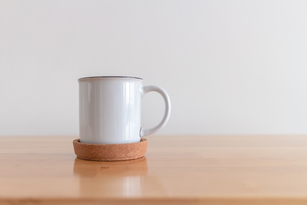 White cup of hot coffee mug on wooden table with white background.