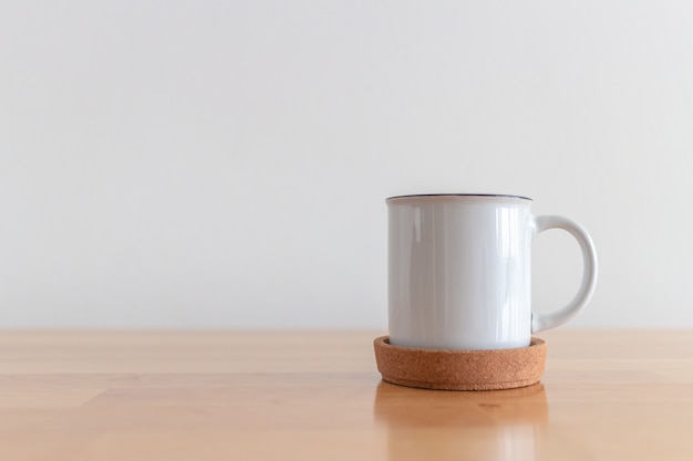 White cup of hot coffee mug on wooden table with white surface