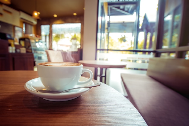 White cup of hot coffee on table in cafe