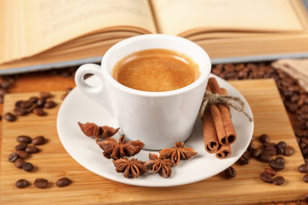 写真 焙煎コーヒー豆のに囲まれたコーヒーエスプレッソの白いカップ