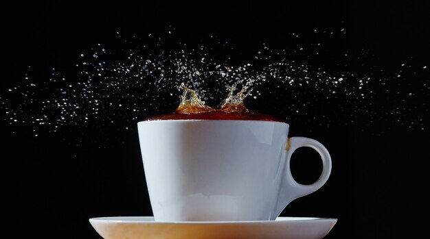 White cup and saucer with a splash of coffee.