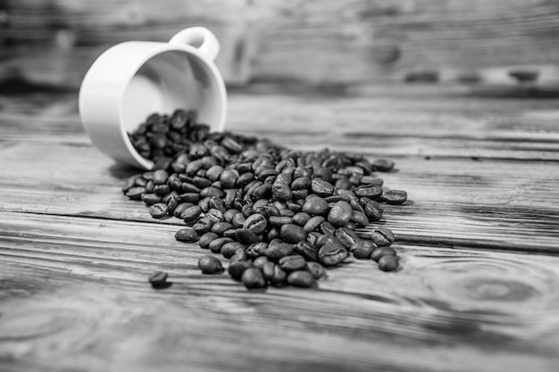 White cup and scattered coffee beans on wooden table