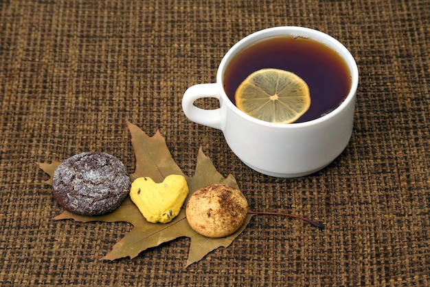 White cup of tea with lemon and biscuits