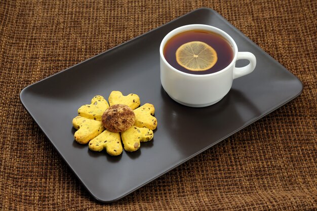 White cup of tea with lemon and biscuits