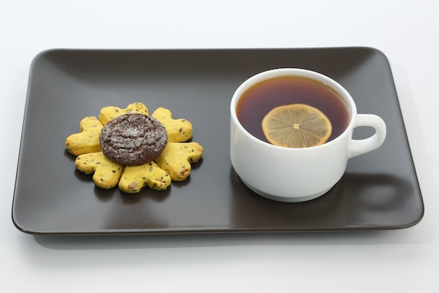 White cup of tea with lemon and cookies