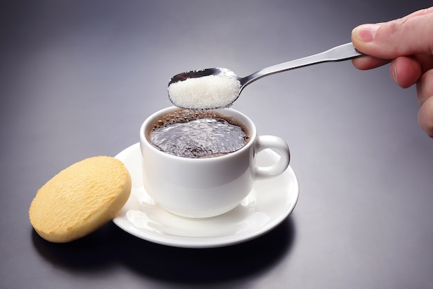 Tazza bianca con caffè nero e cucchiaio con zucchero