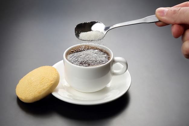 White cup with black coffee and spoon with sugar
