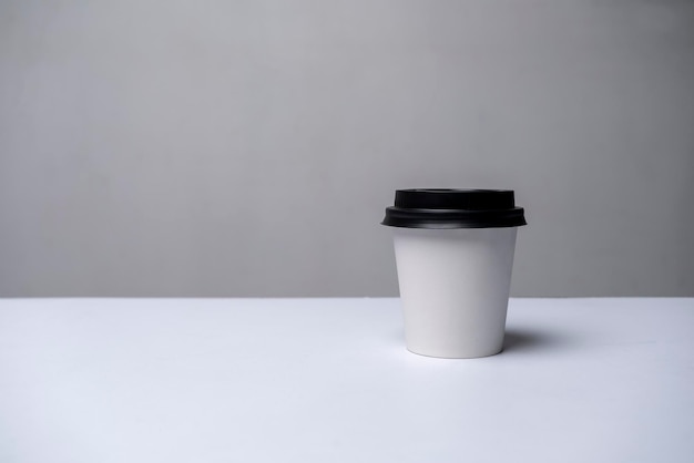 Photo a white cup with a black lid mockup gray background