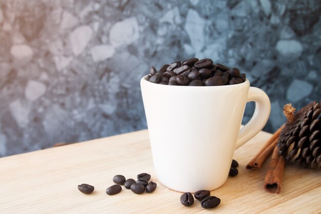 White cup with coffee beans on wooden table