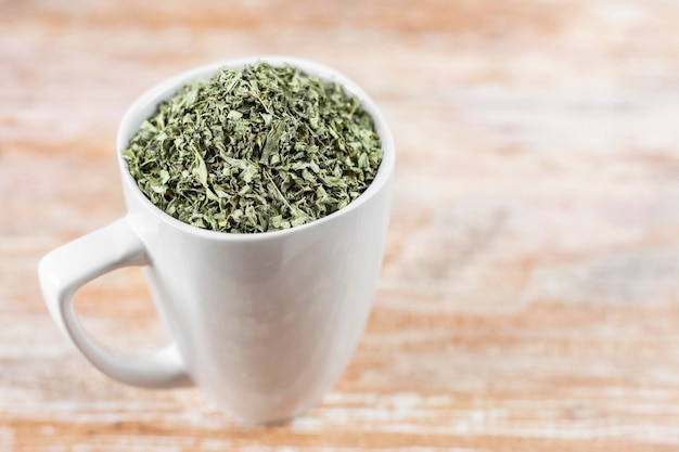 White cup with moringa leaves on wooden background