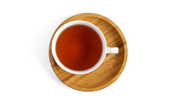 White cup with tea on wooden saucer on white