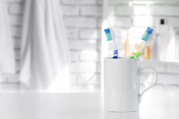 White cup with toothbrushes and towels in bathroom