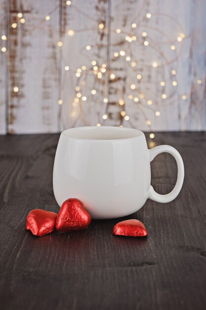 White cup with Valentine chocolate candy red hearts