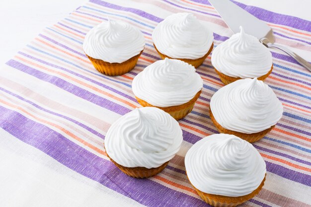 White cupcakes row on the linen napkin