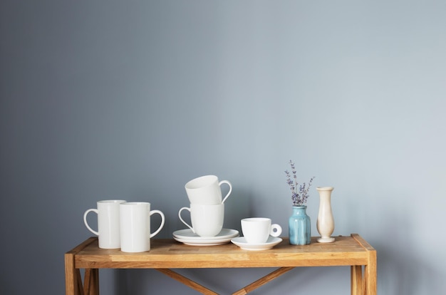 Photo white cups and vases on wooden shelf on gray background