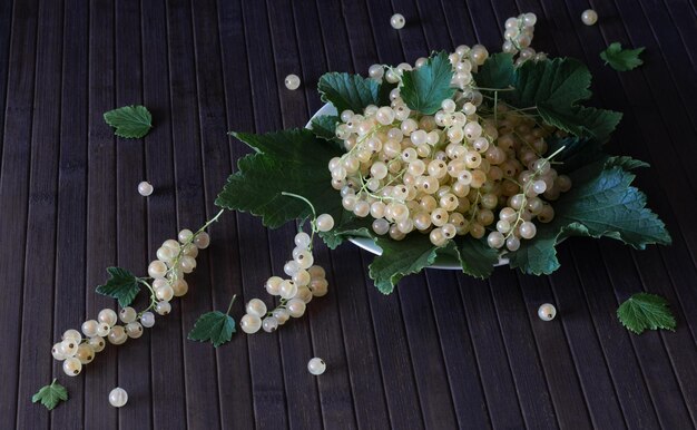 Foto ribes bianco con foglie verdi su uno sfondo di legno scuro.