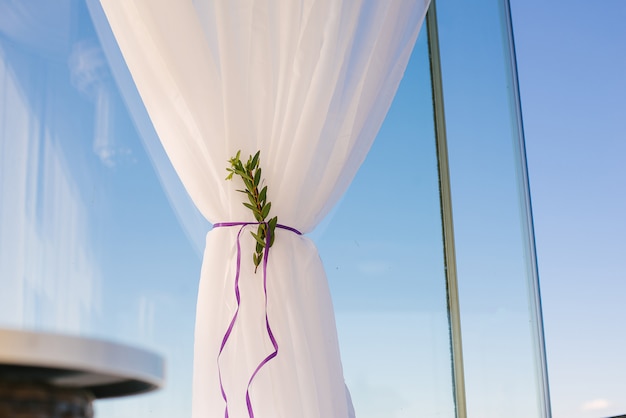 White curtain tied with purple satin ribbon