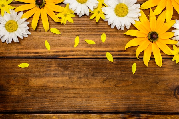 White daisies and garden flowers on a brown wooden table