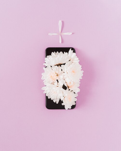 White daisy flowers on a black telephone creating the shape of a grave. Conceptual minimal art.