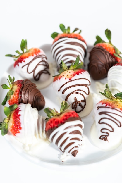 White and dark chocolate dipped strawberries on a white cake stand.