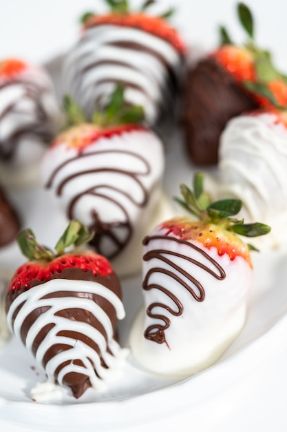 White and dark chocolate dipped strawberries on a white cake stand.