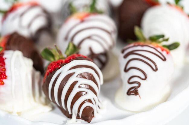 White and dark chocolate dipped strawberries on a white cake stand.