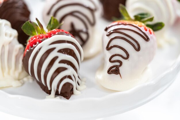 White and dark chocolate dipped strawberries on a white cake stand