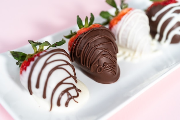 White and dark chocolate dipped strawberries on a white serving plate.