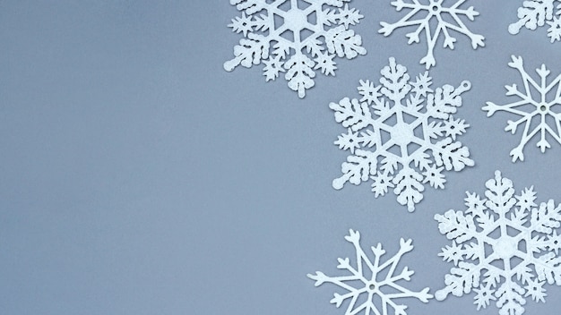 Fiocchi di neve decorativi bianchi su sfondo grigio. natale e capodanno, un luogo per il testo, il minimalismo, lo sfondo invernale