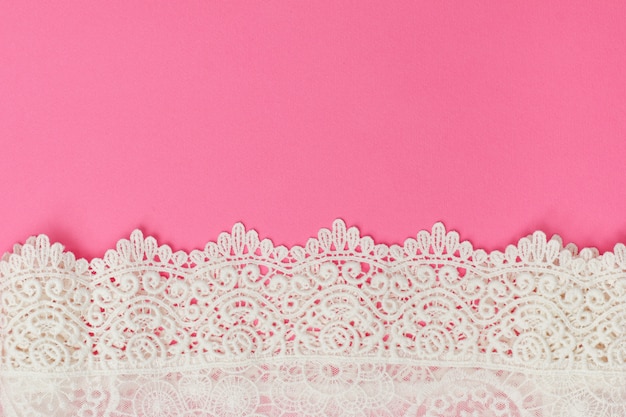 White delicate lace on pink background.