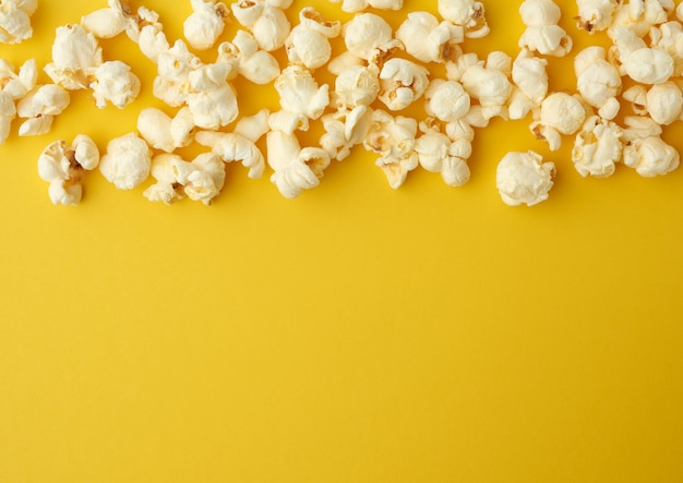 White delicious popcorn on a yellow background, place for an inscription