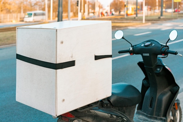 Photo white delivery box installed on a motorcycle stands on the road. service. delivering. transportation. urban. city. business. vehicle