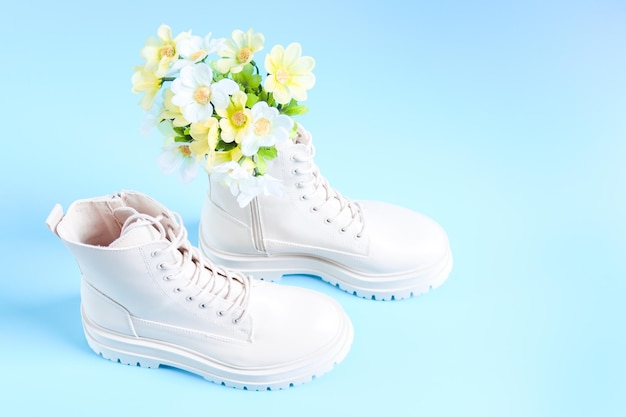 White demiseason martens boots with a bouquet of spring flowers on a light blue