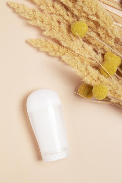 White deodorant and dry pampas grass on beige background